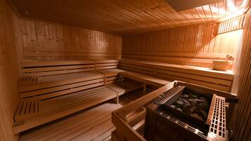 A sauna with wooden benches and a stone basin.