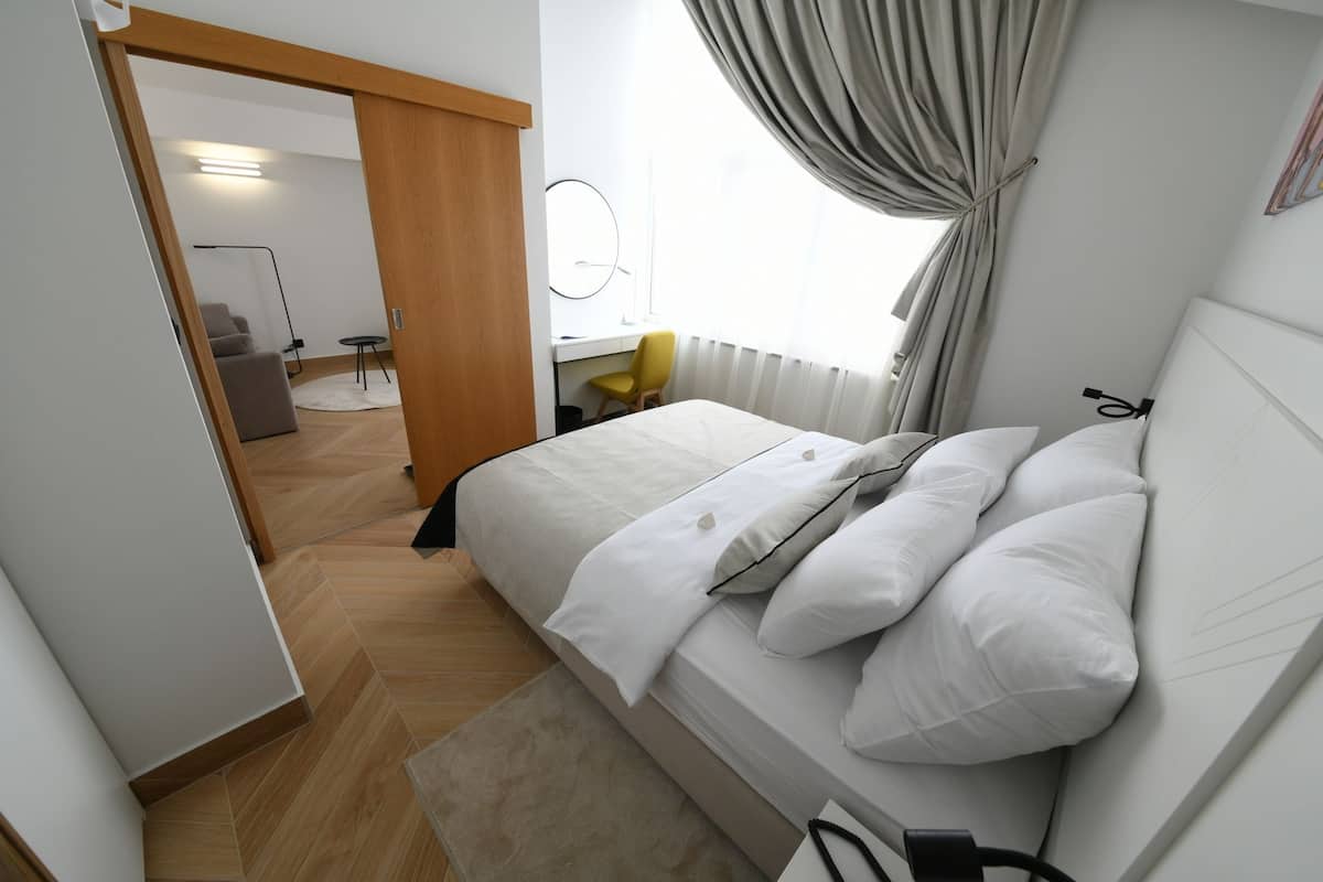 A modern bedroom with a large bed, a desk, and a chair.