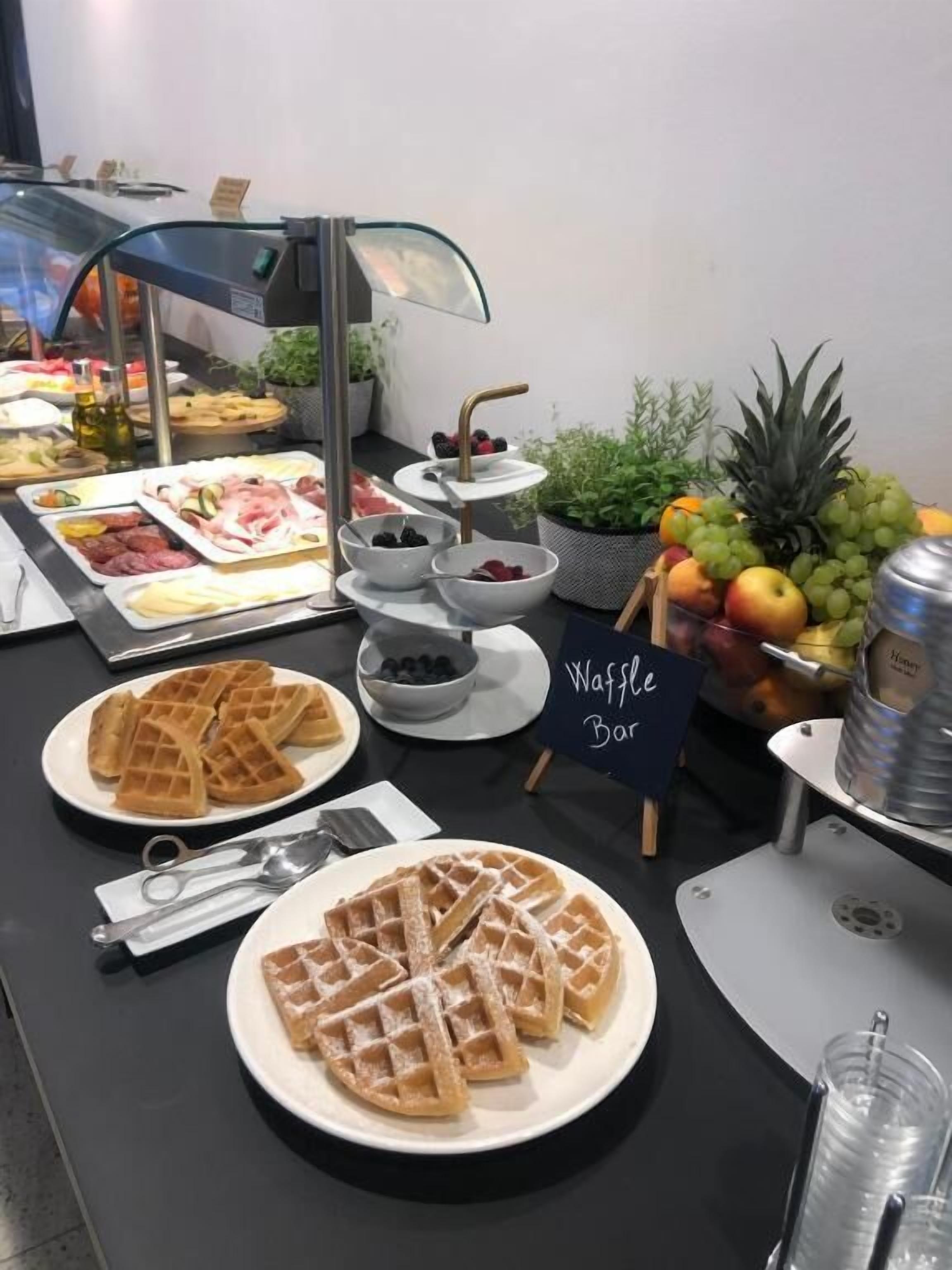 A buffet with waffles, fruits, and a sign for waffle bar.