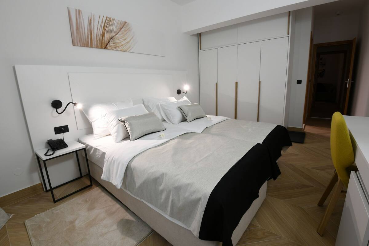A modern bedroom with a bed, bedside table, and a desk.