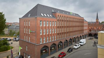 Ein großes Backsteinhaus mit vielen Fenstern und einem Schild für H+Hotel.