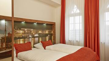 Quarto de hotel com uma cama grande, roupa de cama vermelha e branca, um mural com vista para a cidade na parede e cortinas vermelhas.