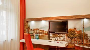 Ein modernes Hotelzimmer mit großem, an der Wand montiertem Fernseher, Stadtblick-Tapete, einem weißen Konsolentisch mit Fernbedienung und einem roten Sessel.