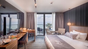 Une chambre d’hôtel avec un lit, un bureau et une chaise, une télévision et un balcon avec vue.