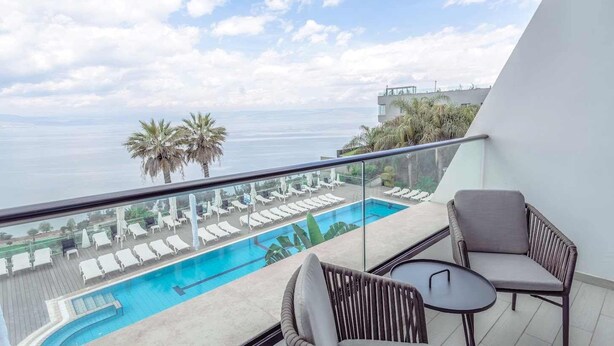 Un balcon avec une piscine, des chaises longues et une vue sur la mer.