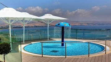 Un área de piscina con diseño circular, rodeada de barandillas de cristal y cubierta con cubierta de madera.