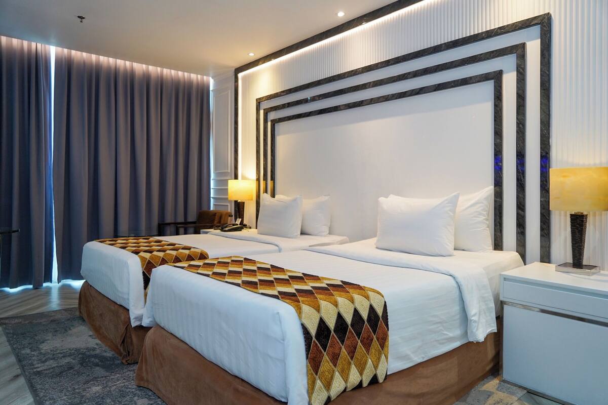 A hotel room with a large bed, two bedside tables, and a headboard with a decorative frame.