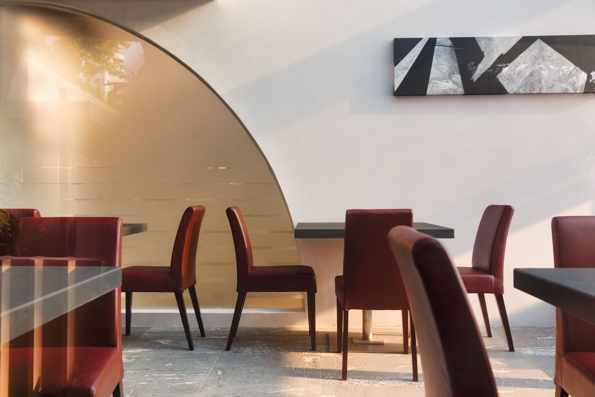 A modern interior with red upholstered chairs and a minimalist design, featuring a curved wall and a simple, clean aesthetic.