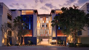 Un hotel moderno con un atrio central, fachada de vidrio y una entrada bien iluminada.
