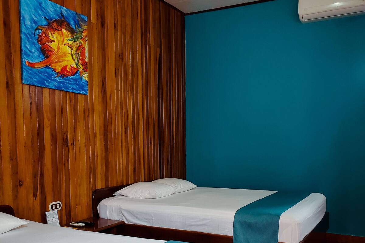 A hotel room with two beds, wooden paneling on one wall, and a blue accent wall.