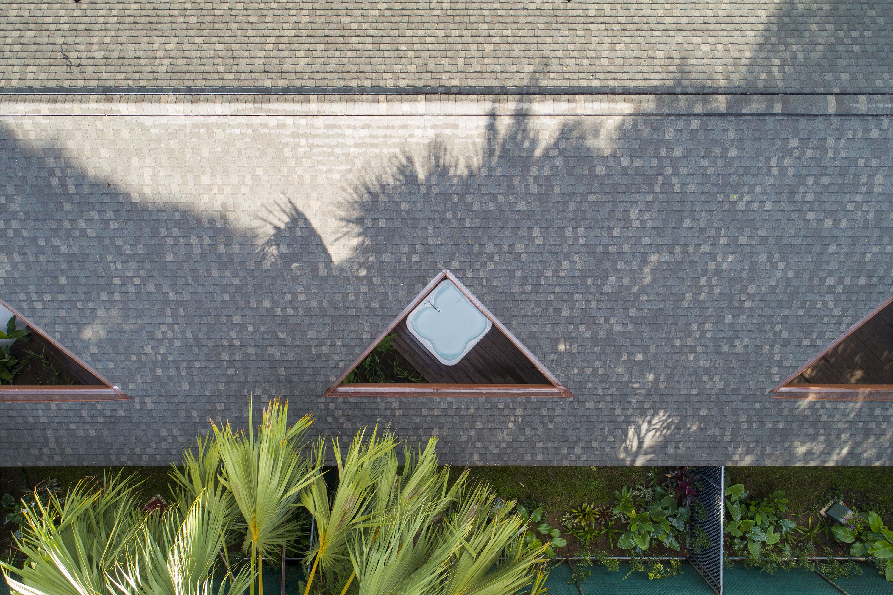 A building facade with a brick pattern and three triangular windows.
