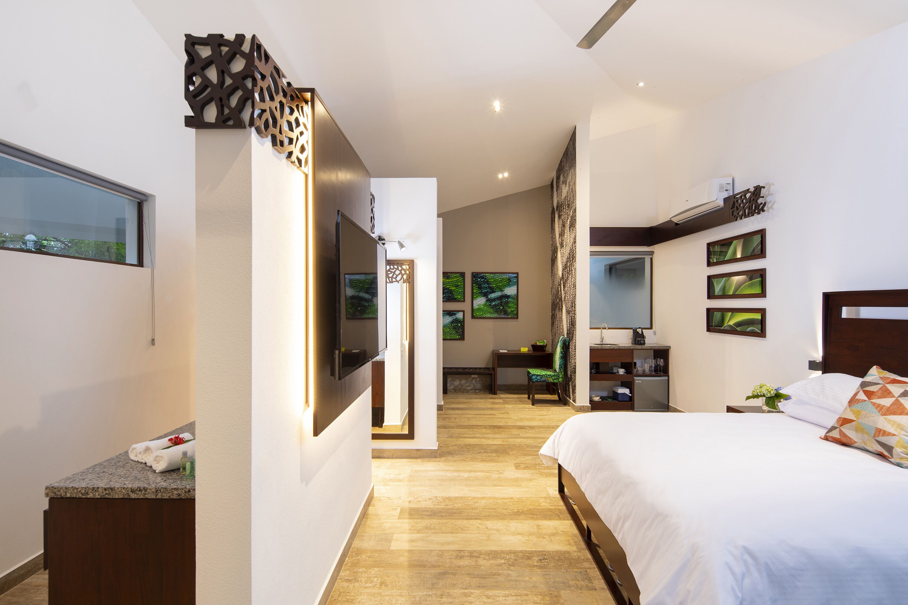 A modern hotel room with a large bed, a desk, and a seating area.