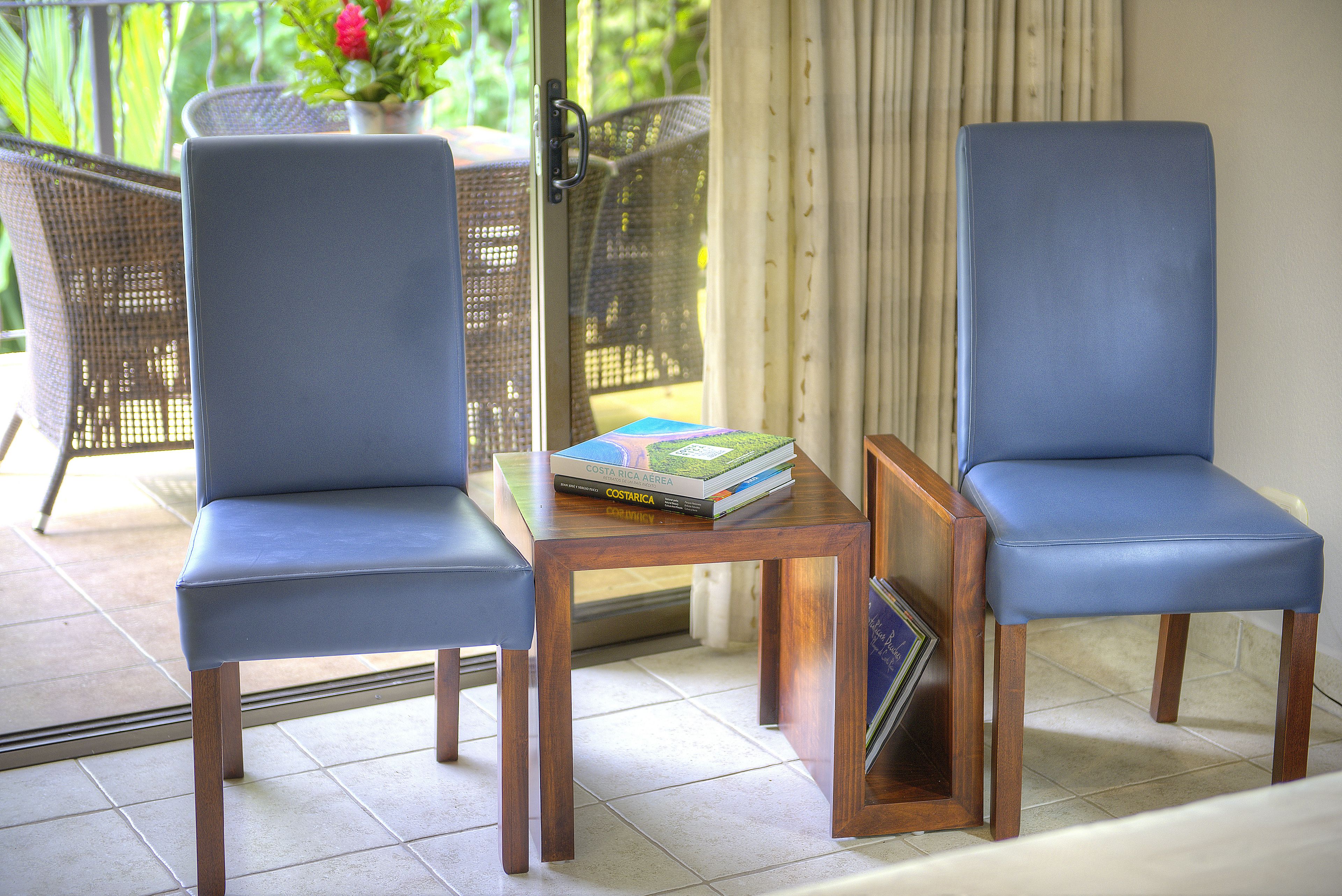 Two blue chairs, a wooden table, and a book titled 'Costa Rica' on the table.