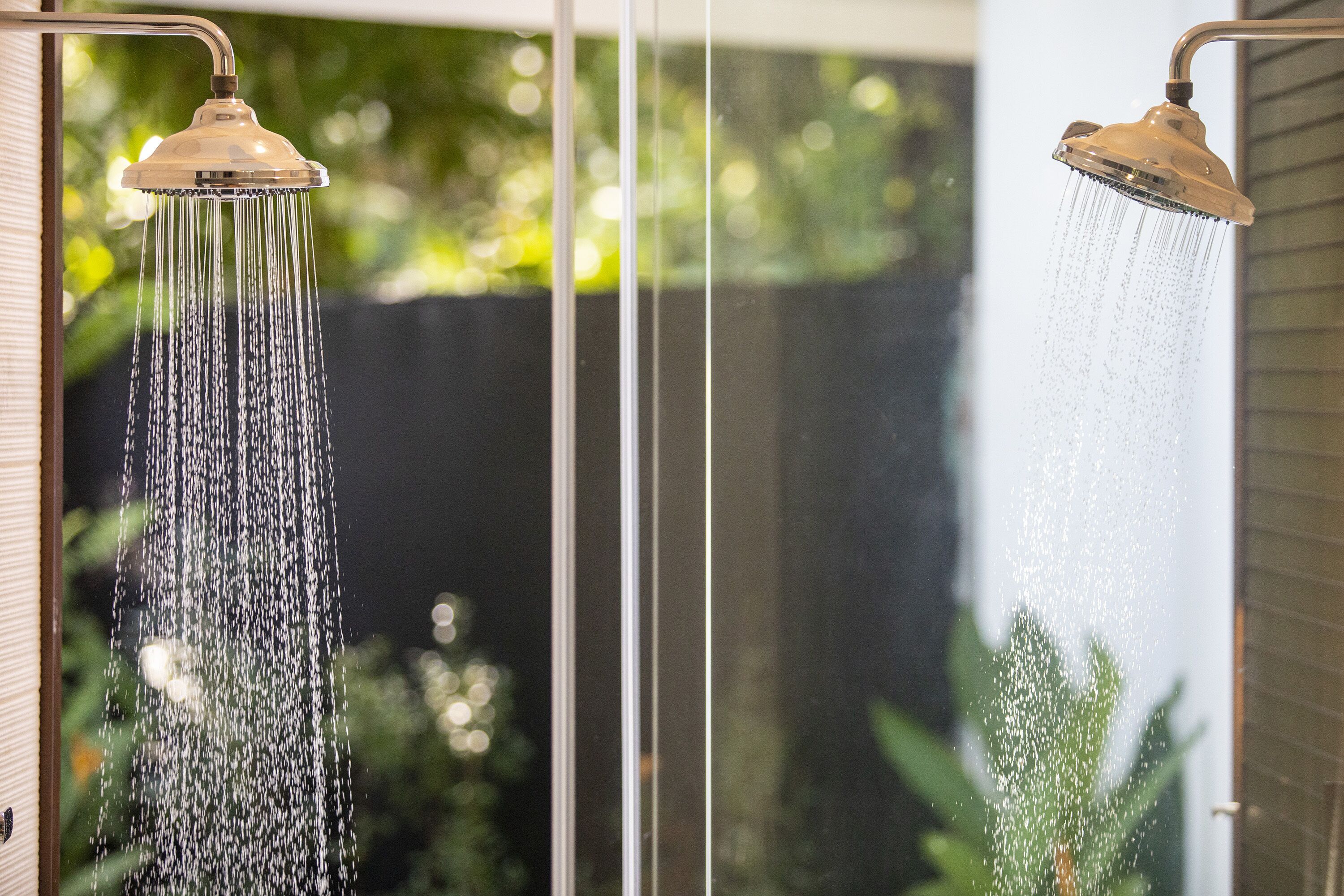 Two showers with water flowing from the heads.