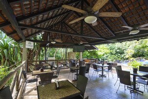 Un patio al aire libre con mesas y sillas, ventiladores de techo y un letrero que dice "EL BOSQUE".