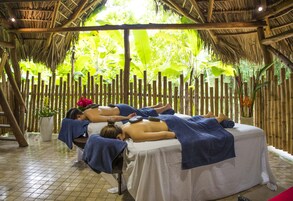 Uma área de spa com camas de madeira, paredes de bambu e um teto de palha.