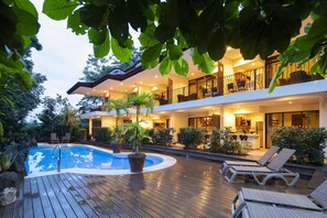 A modern two-story house with a swimming pool, outdoor seating, and lush greenery. - Pumilio Mountain & Ocean Hotel (Jacó)