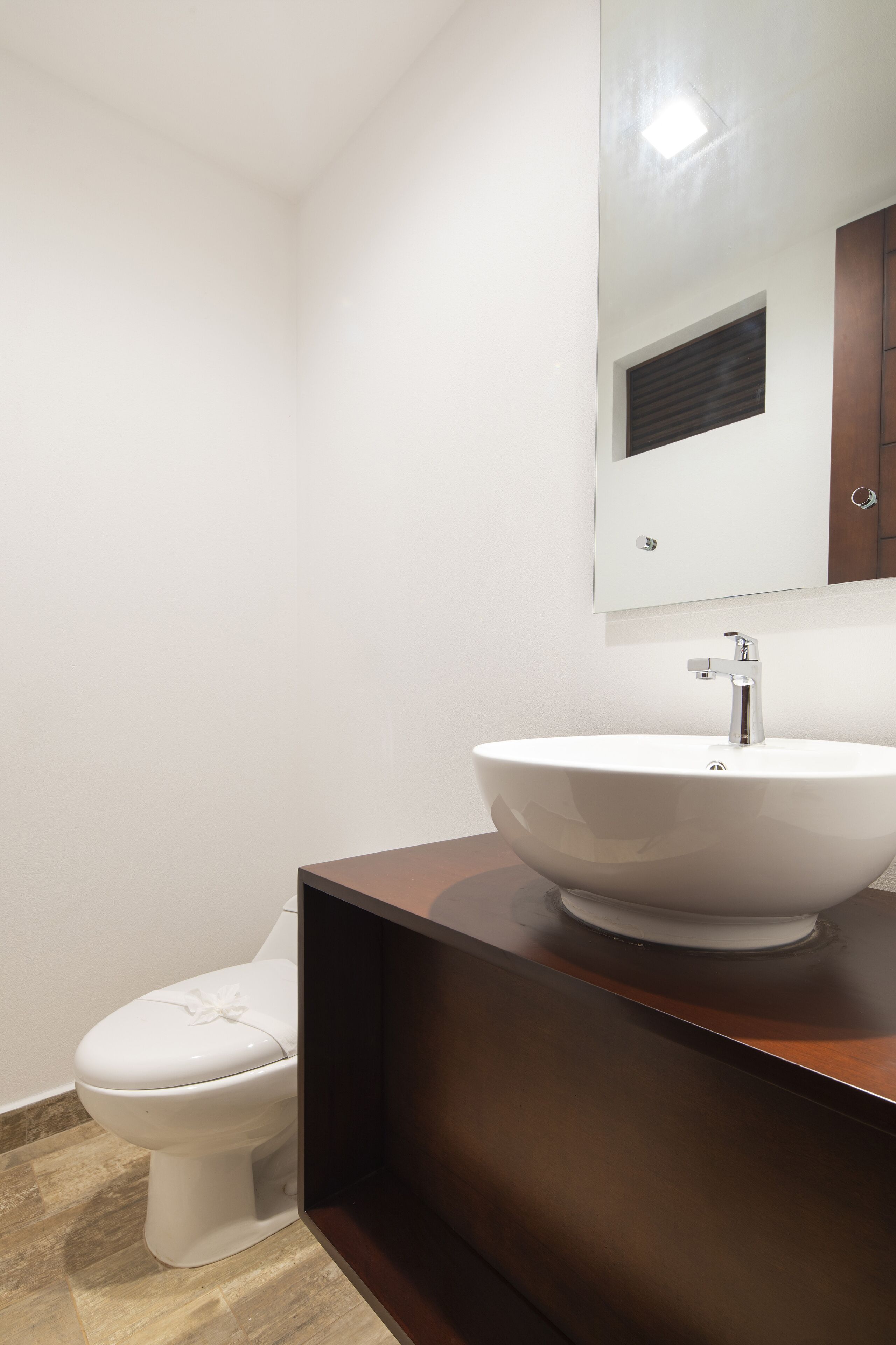 Une salle de bain avec des toilettes blanches, un lavabo sur colonne et un miroir au-dessus du lavabo.