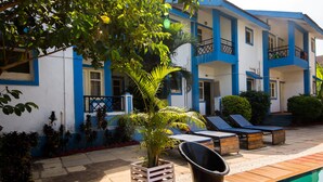 A two-story building with balconies, a swimming pool, and outdoor seating.