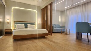 A modern hotel room with a wooden bed, a seating area with a blue chair, and a large window with curtains.