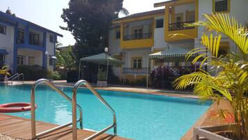 Una piscina al aire libre, sombrillas, tumbonas
