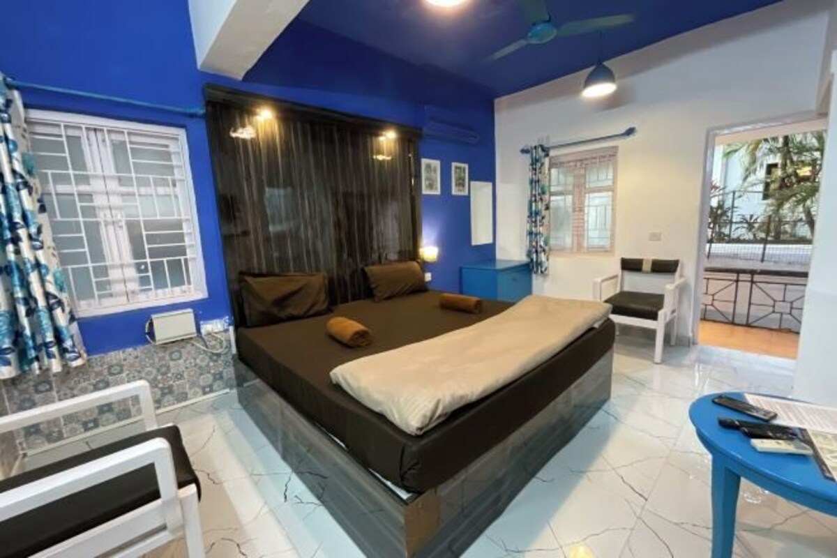 A bedroom with a bed, a desk, a chair, and a window with curtains.