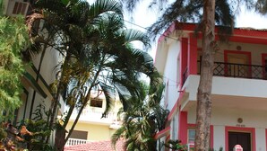 A courtyard with a pathway leading to a building with balconies and a red roof.