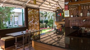 A bar area with a glass counter, bar stools, and a view of a garden through a decorative screen.