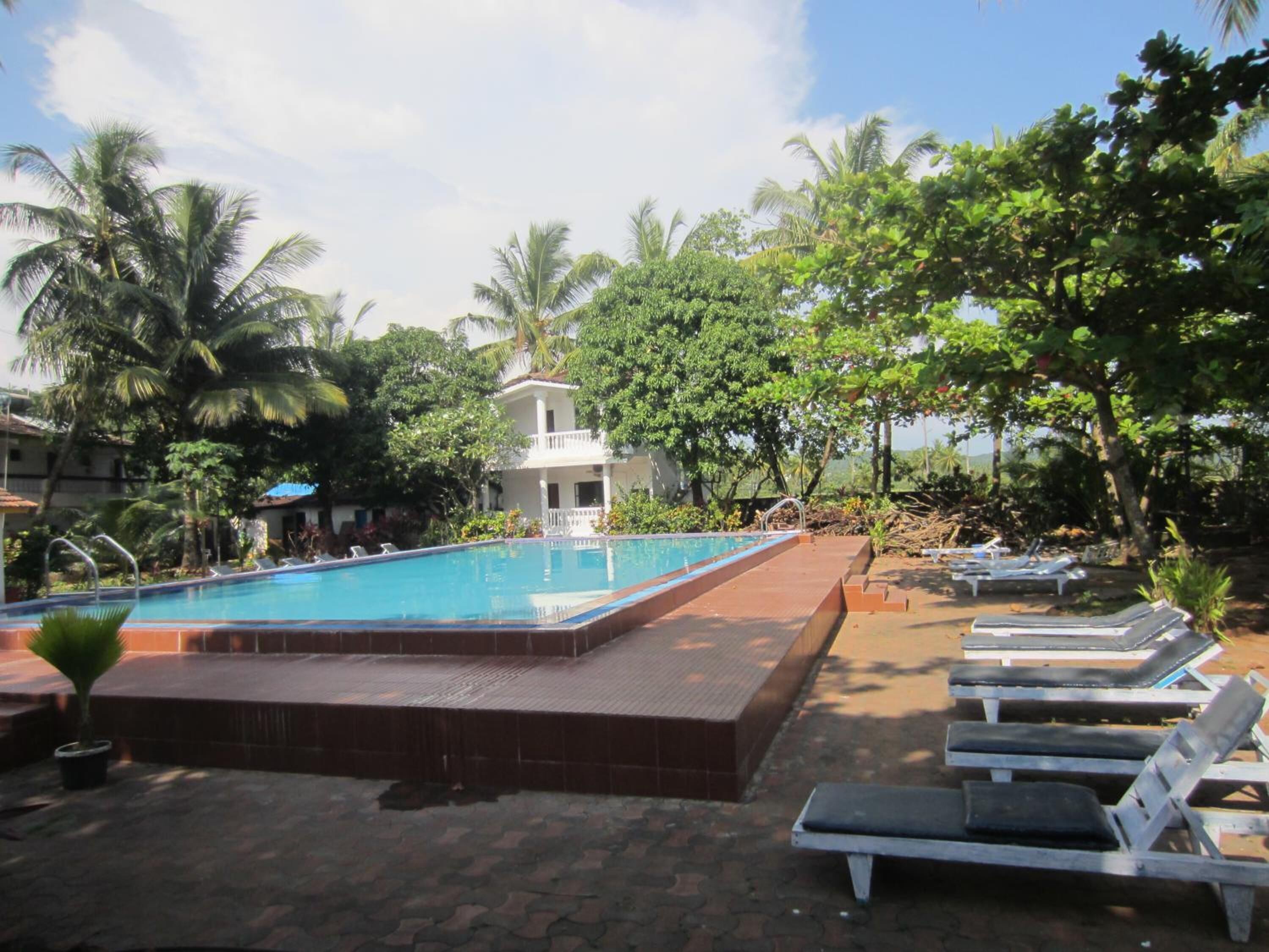 A pool area with lounge chairs, a small pool, and a white building in the background.