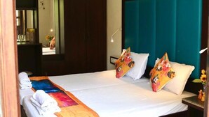 A double bed with a teal headboard, two decorative pillows, and a yellow blanket. - Hotel Riverside (Baga)