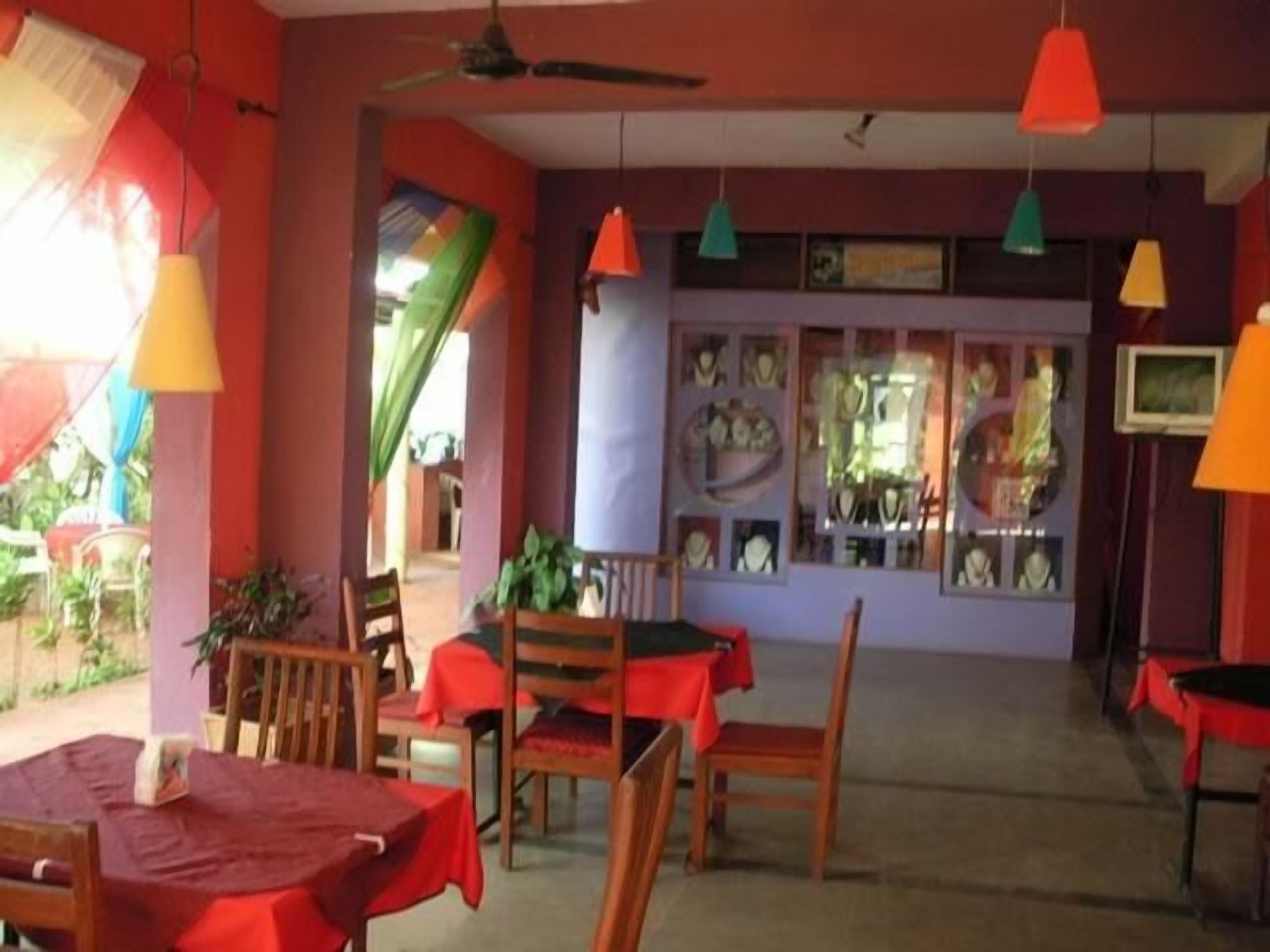 A room with wooden furniture, red tablecloths, and colorful pendant lights.