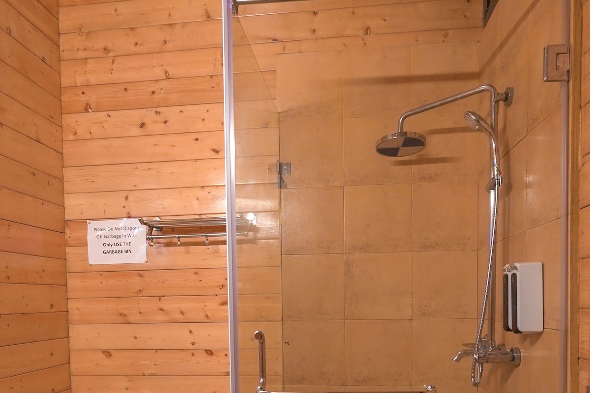 En bruseniche med glasdør, et toilet og et skilt, der informerer om ikke at smide affald i toilettet.