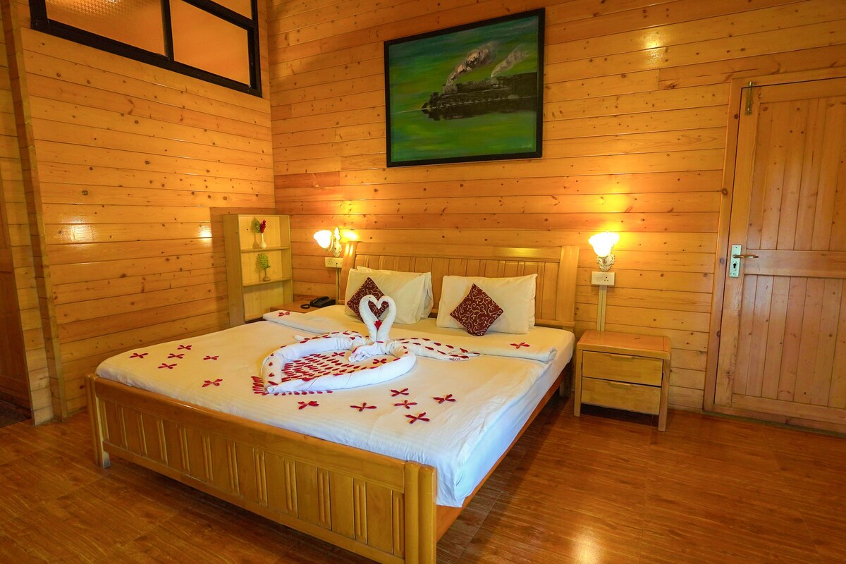 A wooden-paneled room with a bed, bedside tables, a nightstand, and a painting on the wall.