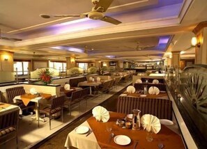 A spacious restaurant with multiple dining tables, ceiling fans, and large windows. - Tio Carmino (Calangute)