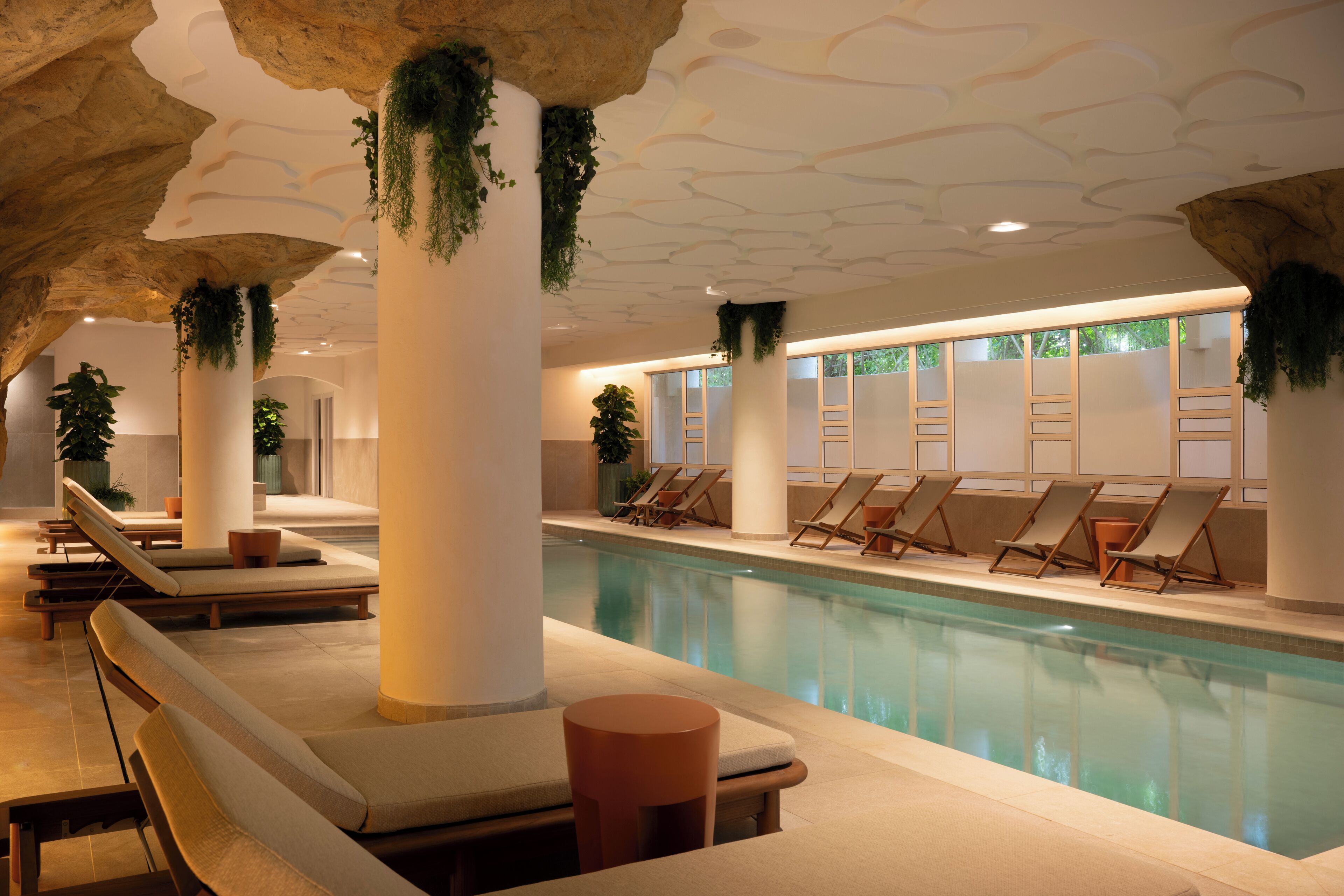 Un área de piscina con sillones de descanso y una gran piscina cubierta.