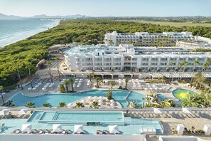 Un complexe hôtelier doté de plusieurs piscines, d’une plage et d’une végétation luxuriante.