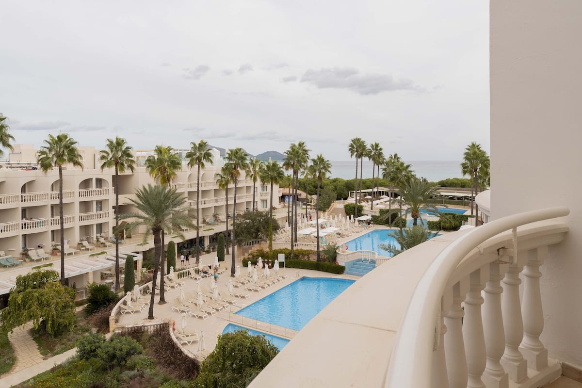 A resort with multiple swimming pools, palm trees, and a view of the sea.