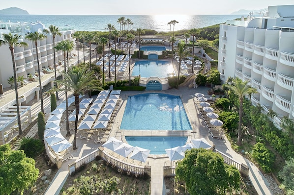 Un complexe hôtelier doté de plusieurs piscines, de palmiers et offrant une vue sur la plage.
