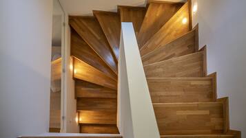 Una escalera espiral de madera con iluminación integrada que conduce a un piso superior.