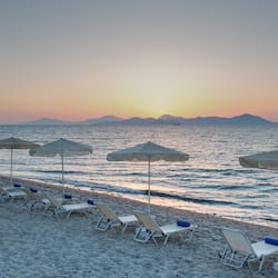Relax on the beach with comfortable sun loungers and umbrellas, overlooking the calm sea.