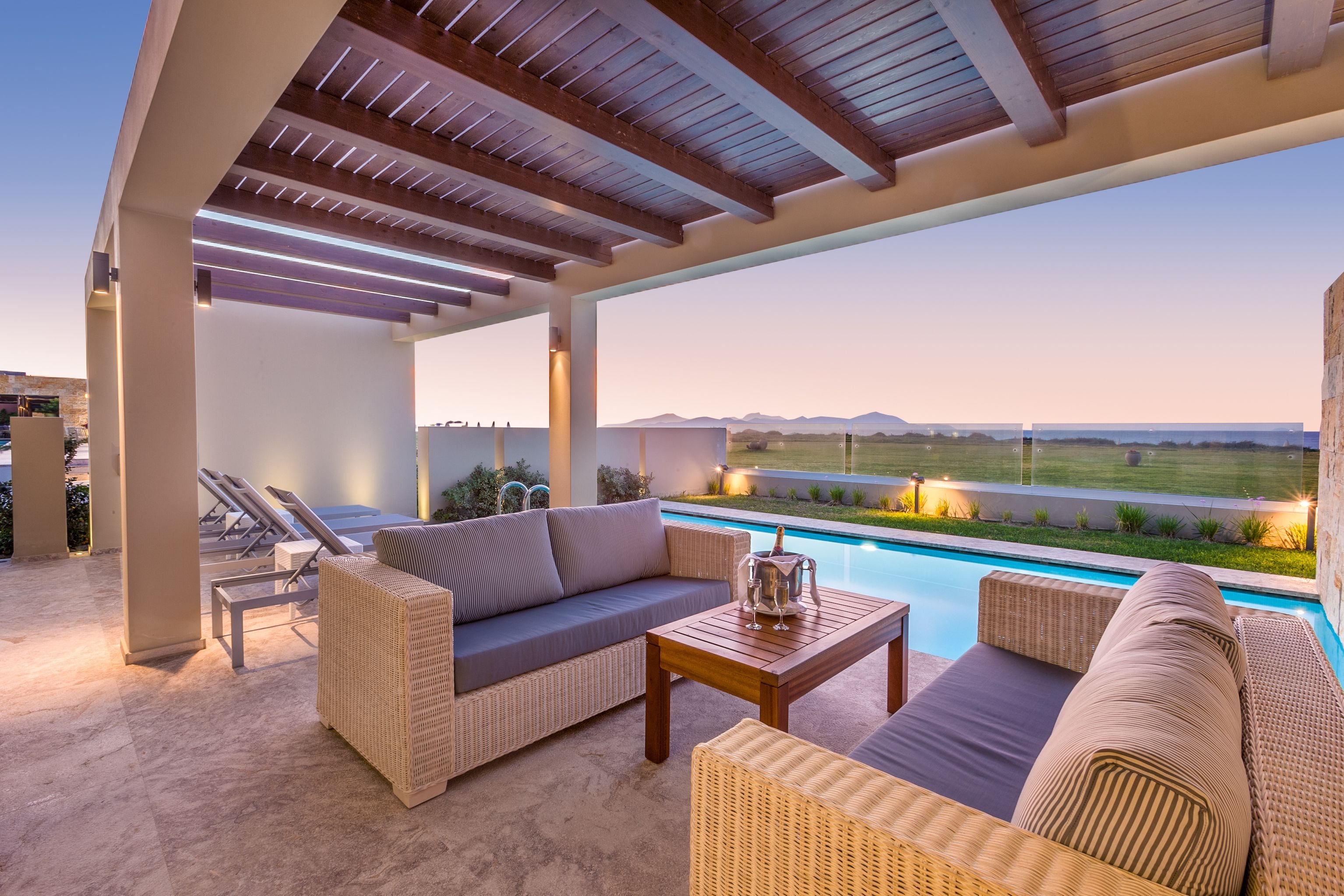 Un patio al aire libre con mobiliario de mimbre, una piscina y vistas del paisaje.