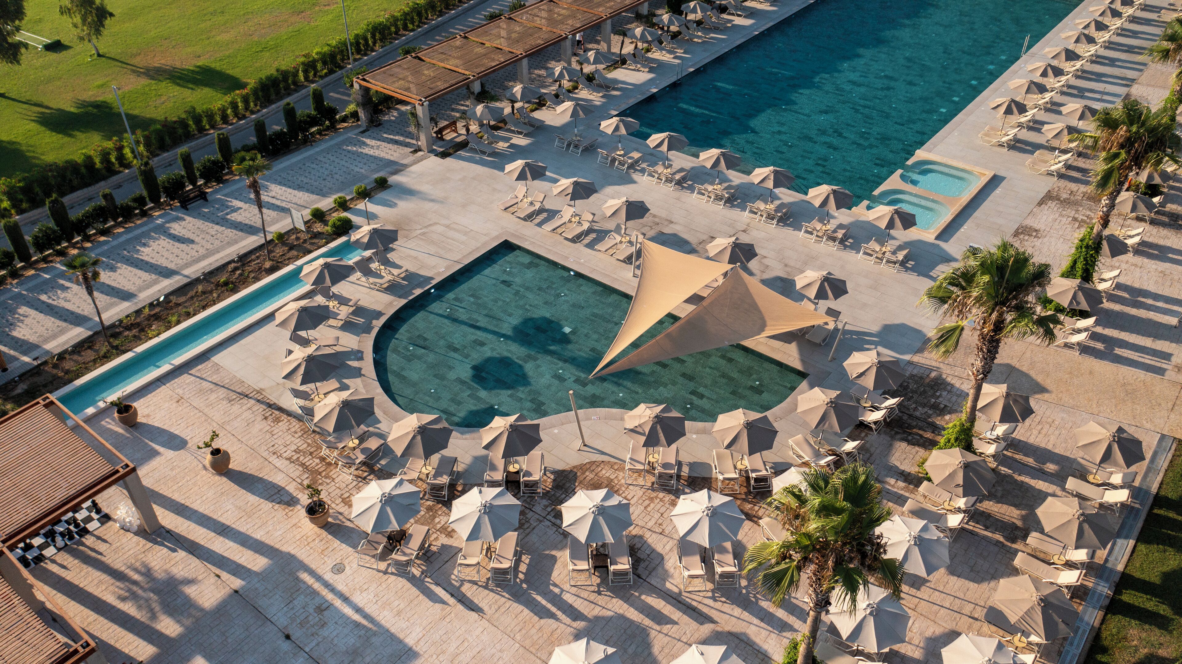 An aerial view of a resort with multiple swimming pools, sun loungers, and umbrellas.