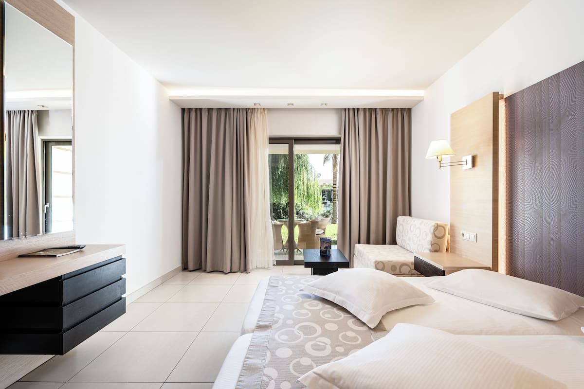 A modern hotel room with a bed, bedside table, and a view of the outdoors.