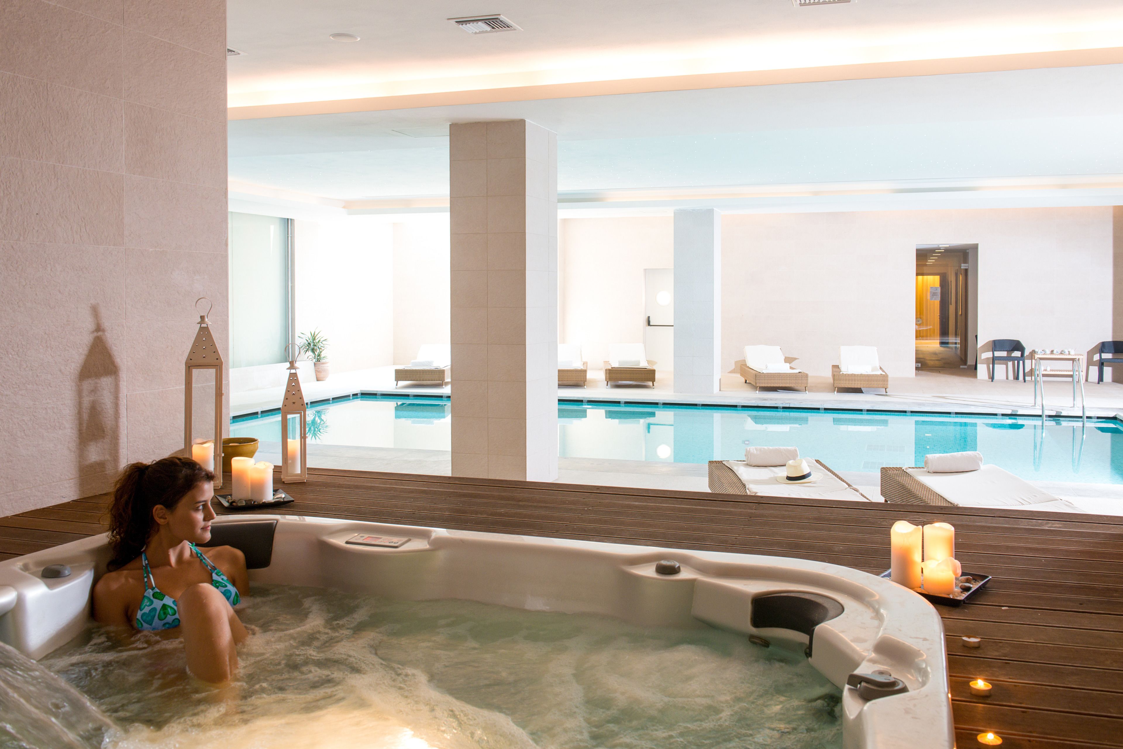 A spa area with a hot tub, lounge chairs, and a pool.