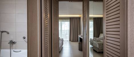A hotel room with a bathtub, a bed, a desk, and a mirror.