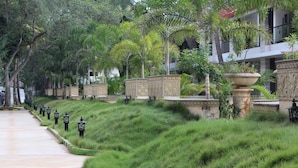 A pathway lined with grass and decorative planters, leading to a building with a modern architectural style. - VGP Golden Beach Resort (Chennai)