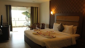 A hotel room with a bed, a desk, a chair, and a balcony with curtains. - VGP Golden Beach Resort (Chennai)