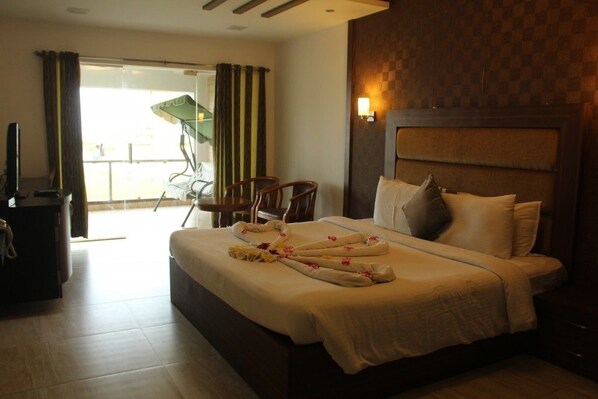 A hotel room with a bed, a desk, a chair, and a balcony with curtains. - VGP Golden Beach Resort (Chennai)