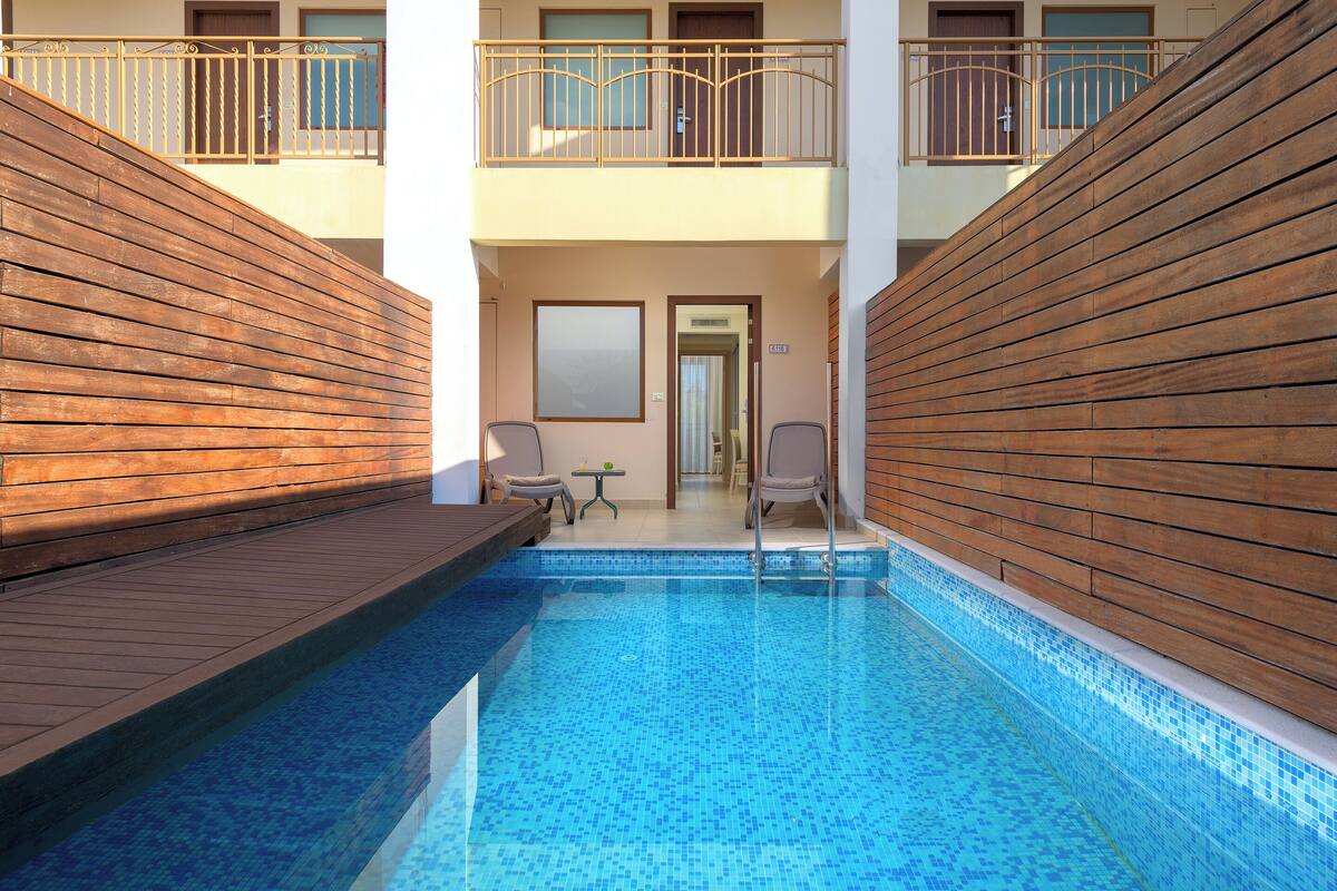 A swimming pool with wooden deck, a small table, and two chairs.
