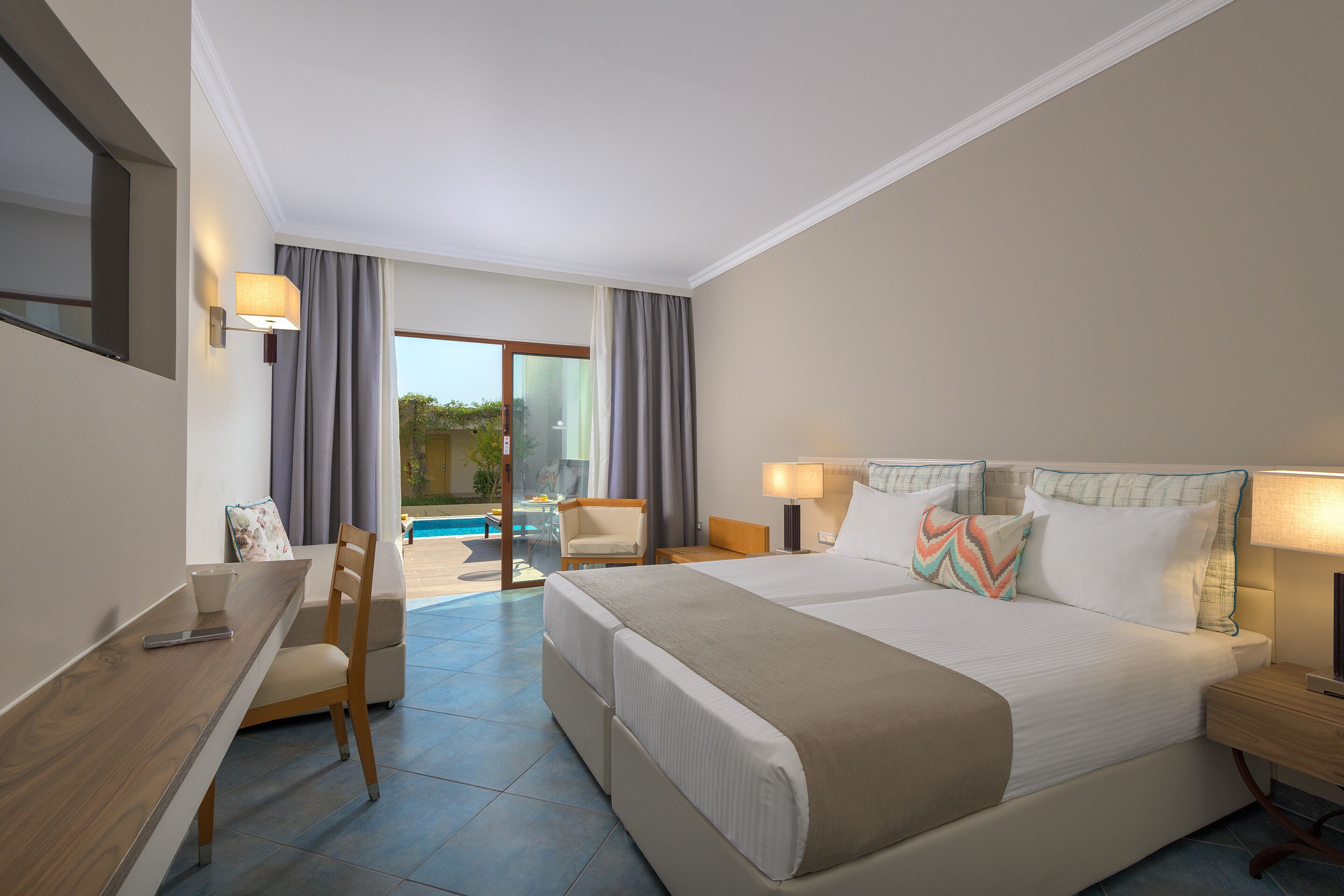A hotel room with a large bed, a desk, a chair, and a view of a pool.
